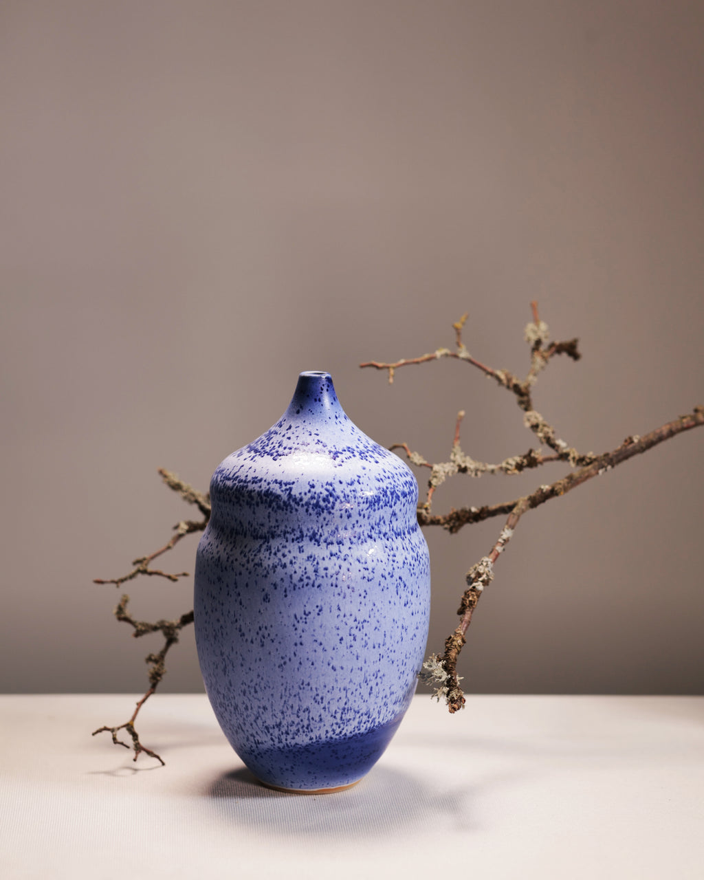 Blue ceramic vase with speckled texture on a neutral background