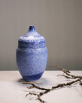 Blue ceramic vase with speckled texture on a neutral background