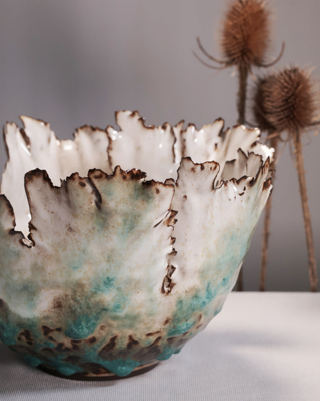 Ceramic bowl with textured surface and teal and brown colors on a neutral background