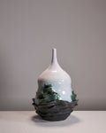 White ceramic vase with green accents on a gray background