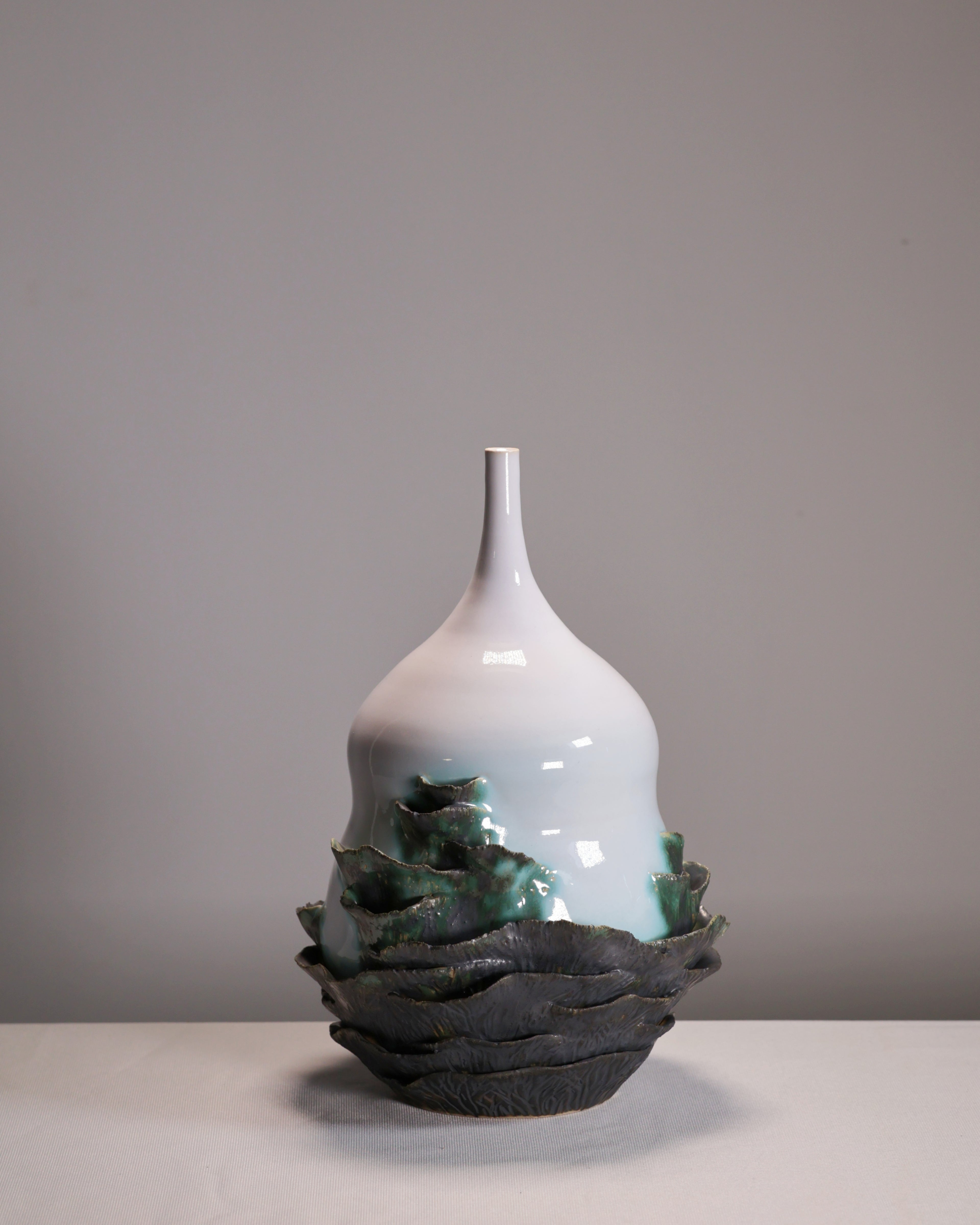 White ceramic vase with green accents on a gray background