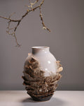 Vase with layered design and natural elements on a gray background