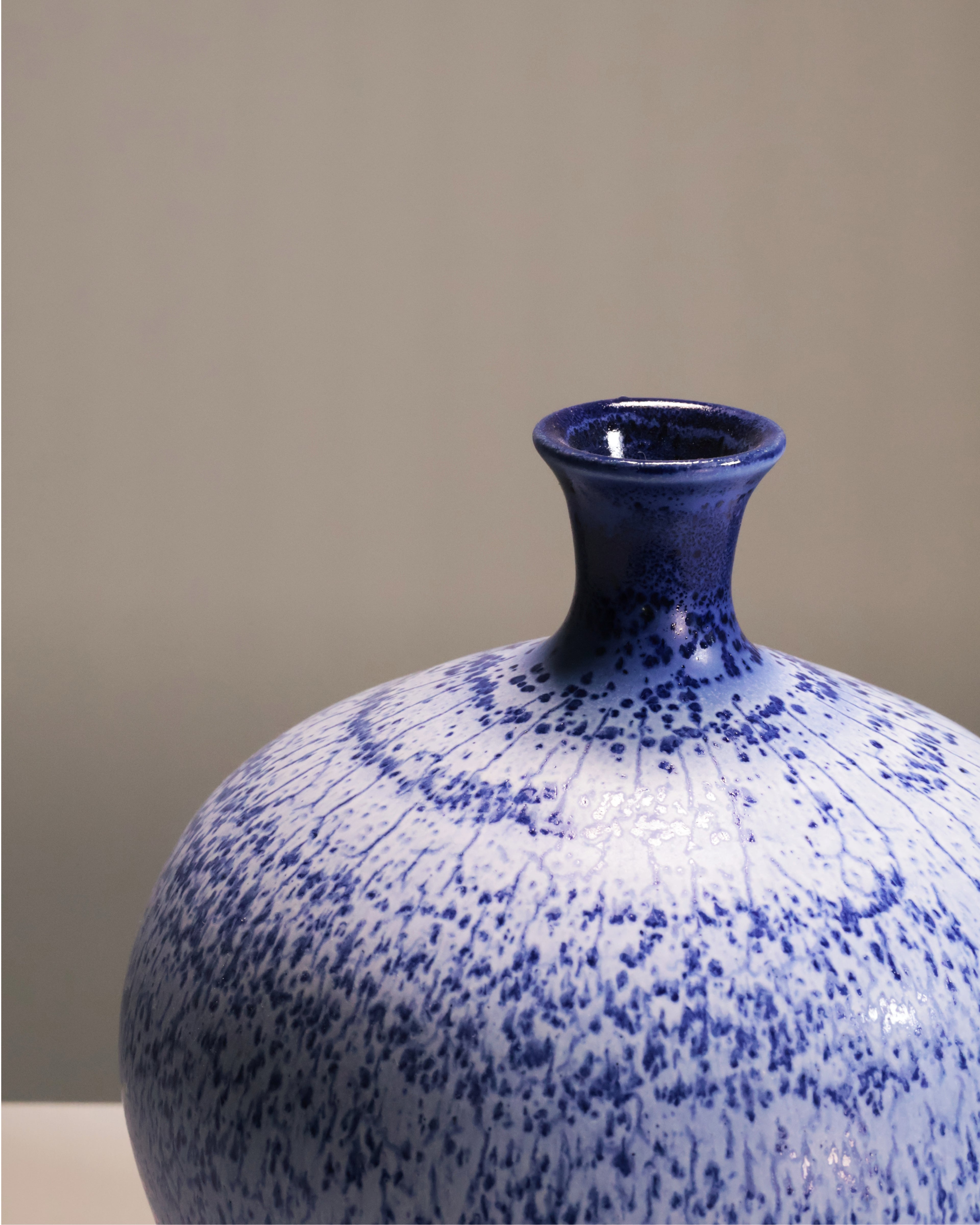 Blue and white speckled ceramic vase on a neutral background