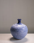 Blue speckled vase on a gray surface with a gray background